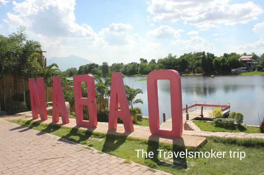 A sign with the letters 'NABAQ' in red, a lake, and a bridge in the background.