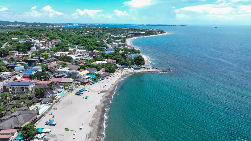 A coastal town with a beach, buildings, and a clear view of the ocean.