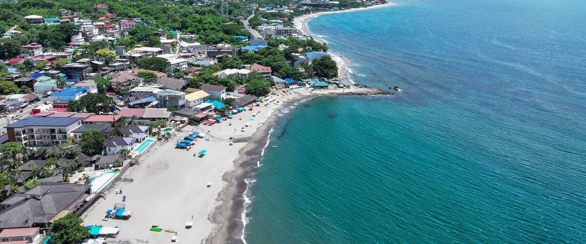A coastal town with a beach, buildings, and a clear view of the ocean.