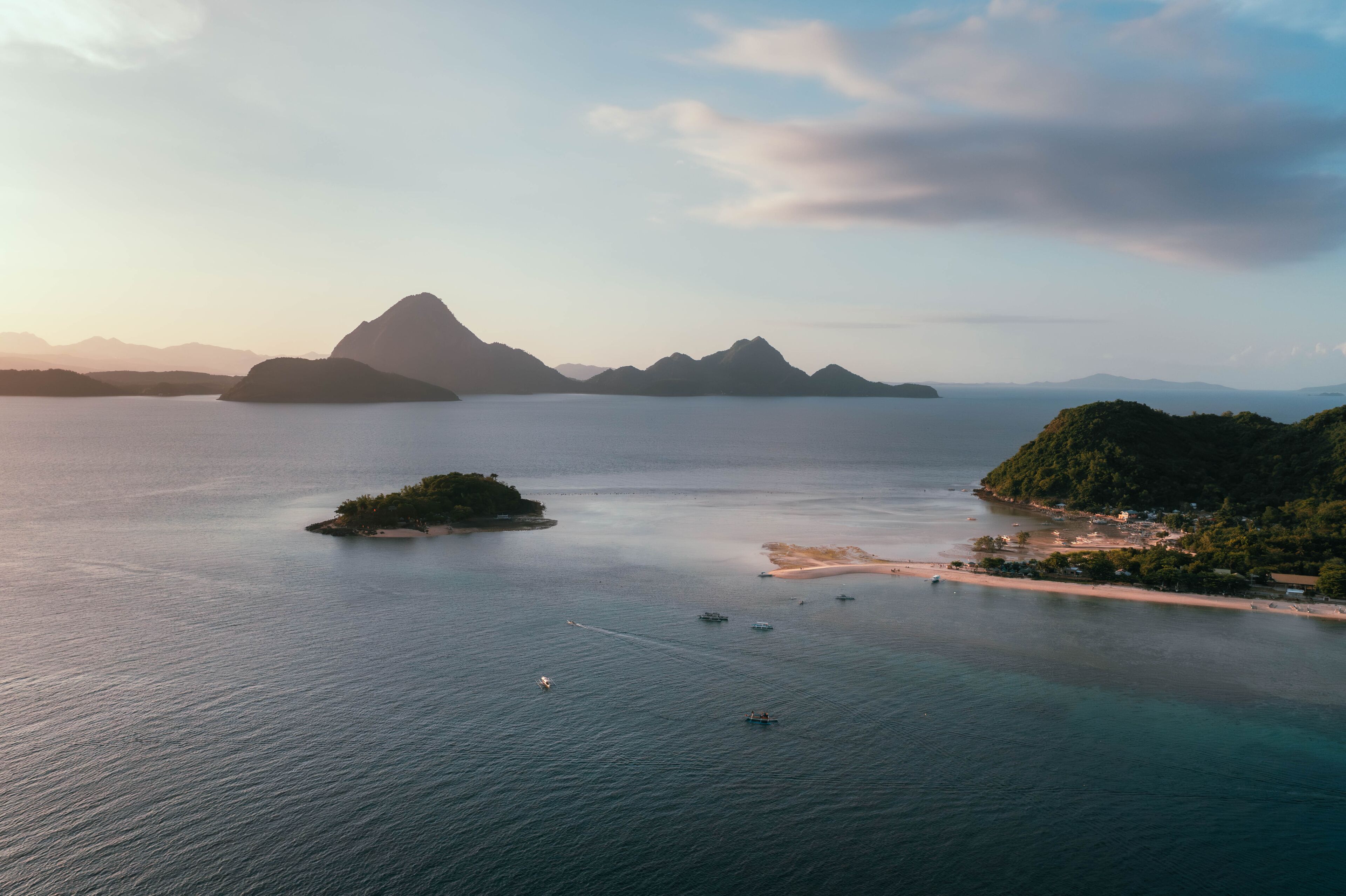 Aerial view of a tranquil seascape dotted with verdant islands, where the sky blends seamlessly with the sea, Bagosipol Island, Concepcion, Philippines.