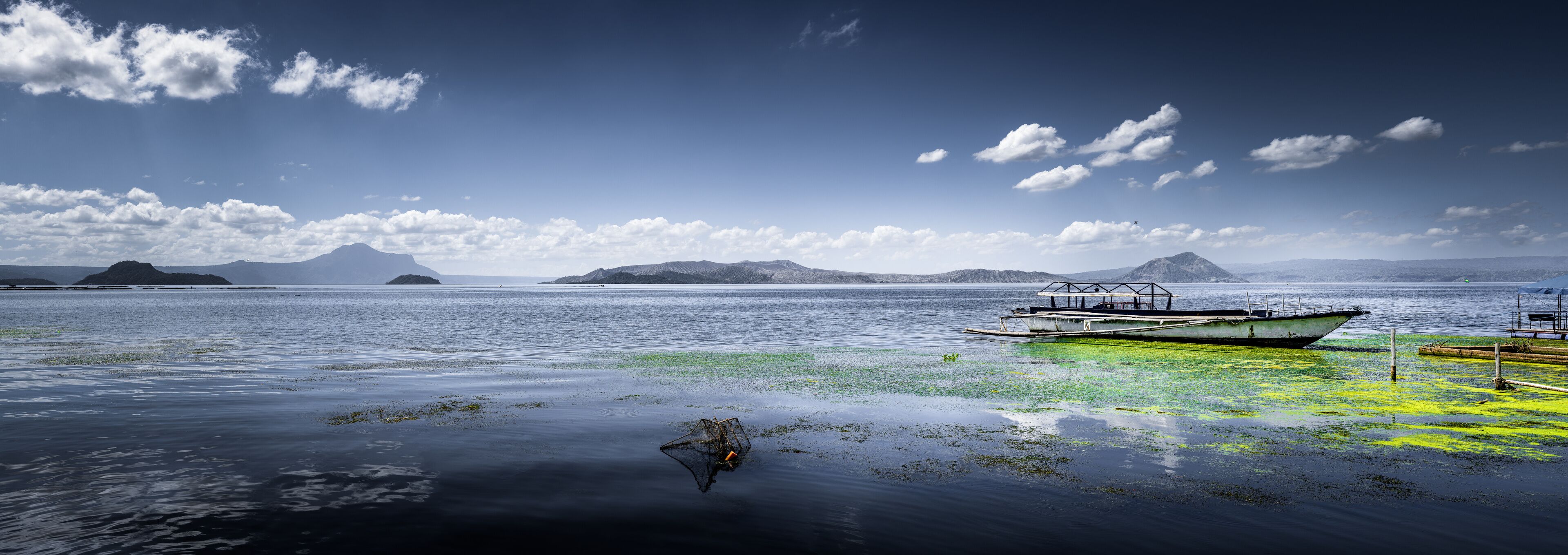 A boat on calm water with distant mountains and a clear sky.