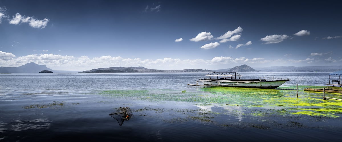 A boat on calm water with distant mountains and a clear sky.