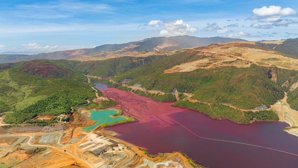 Open pit nickel mine and burgundy water lake. Polluted air and water. Mindanao, Philippines.