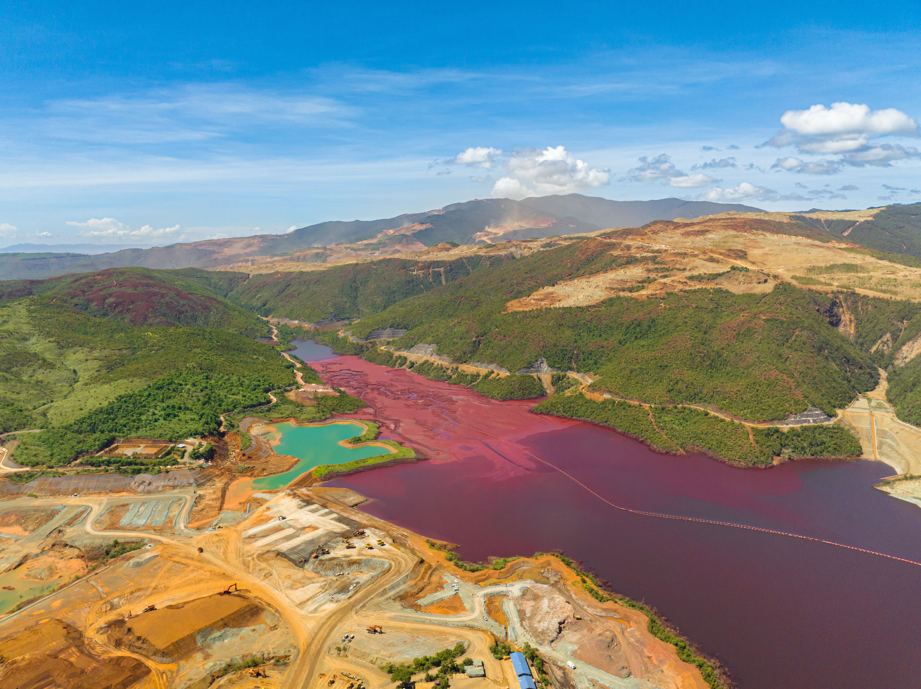 An aerial view of a mining area with a large body of water and surrounding hills.