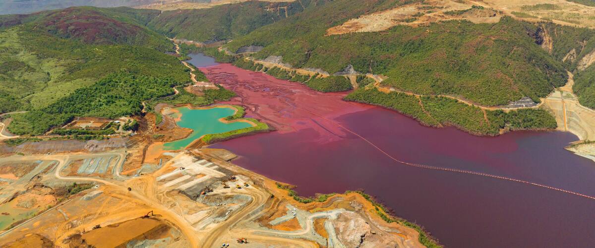 An aerial view of a mining area with a large body of water and surrounding hills.