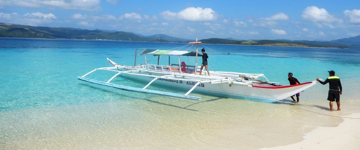 A clear blue sea with a boat on the shore.