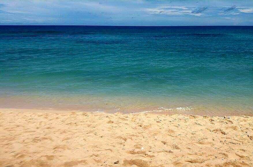 A sandy beach with clear turquoise water.