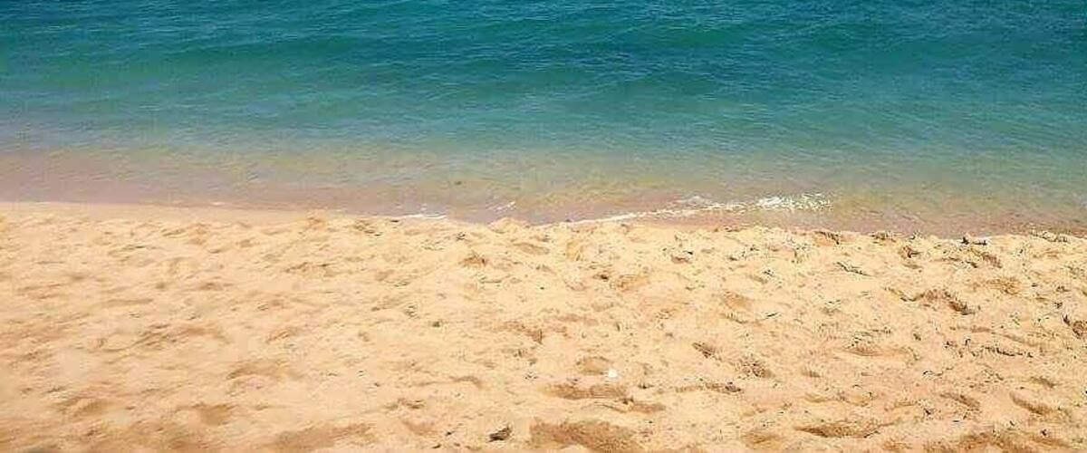 A sandy beach with clear turquoise water.
