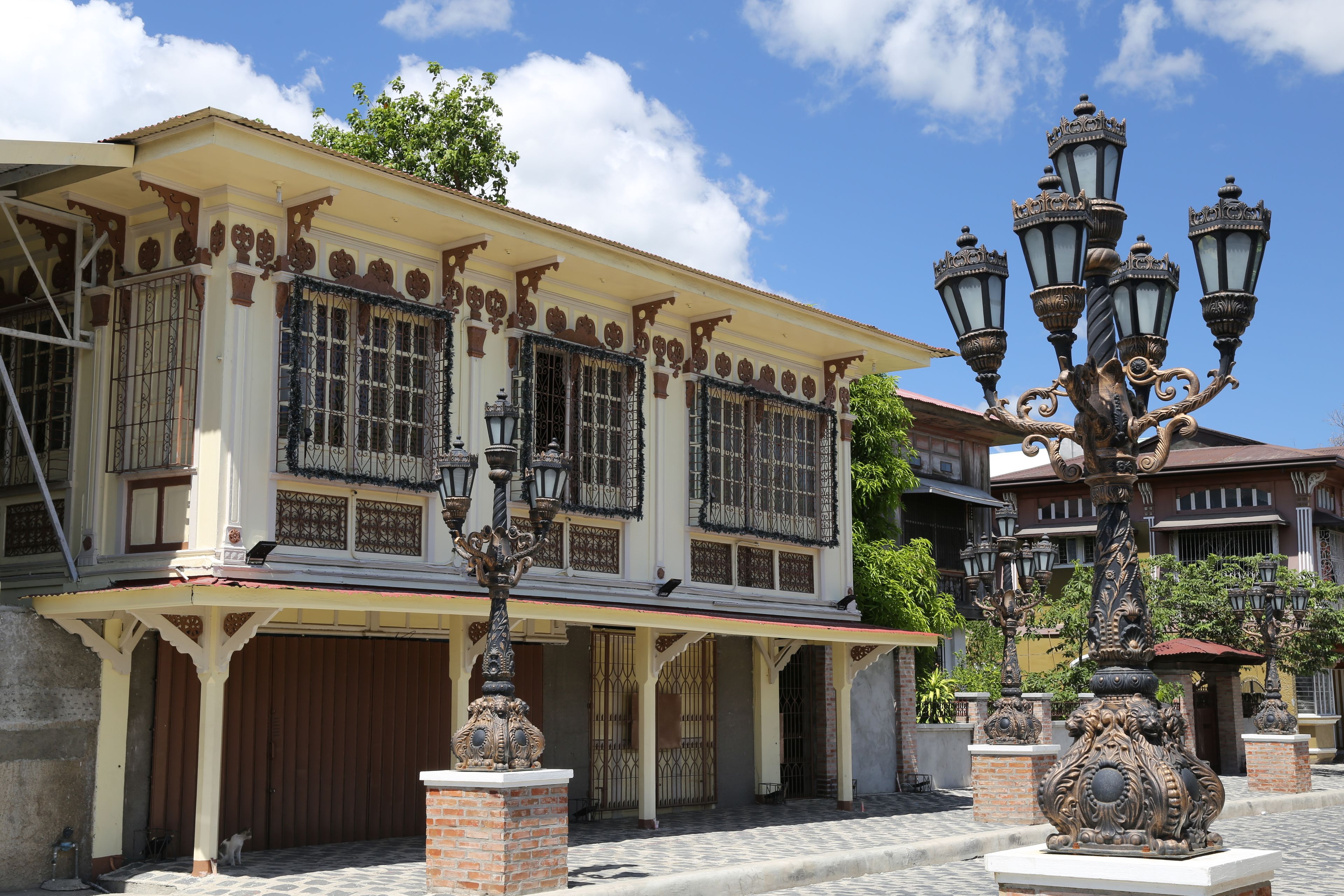 A historic building with ornate ironwork, a covered porch, and decorative street lamps.
