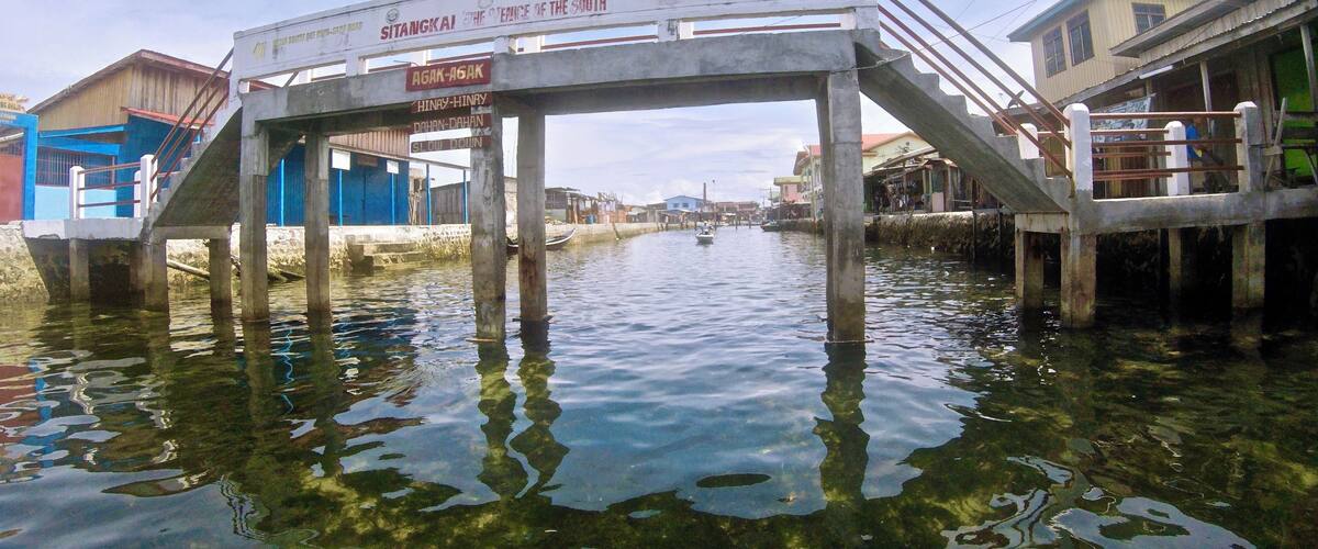 A bridge over water with signs indicating directions to various locations.