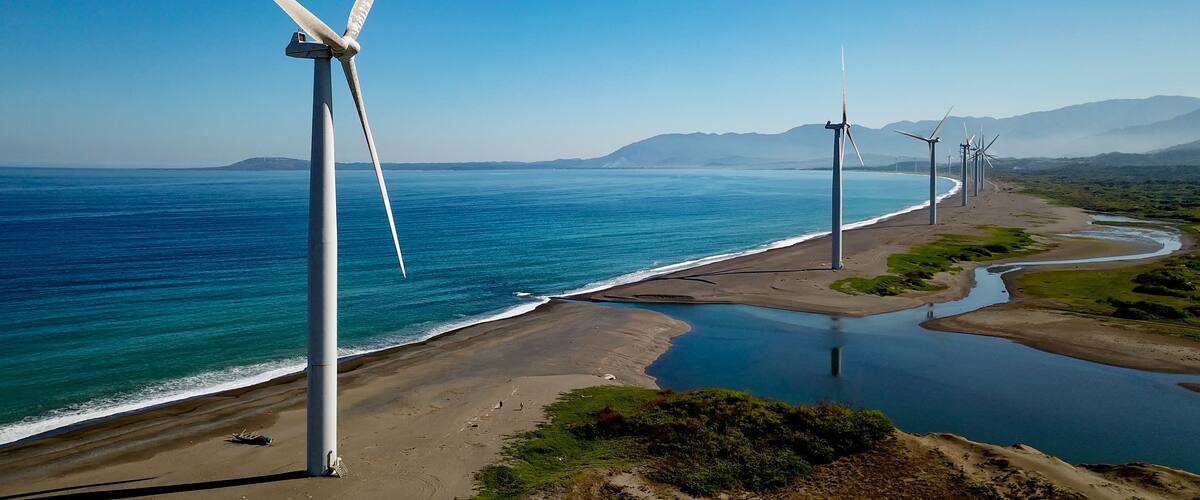A coastal landscape with wind turbines and a calm sea.