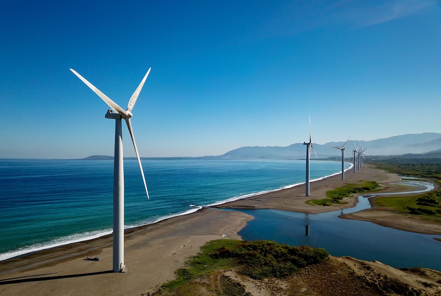 A coastal landscape with wind turbines and a calm sea.