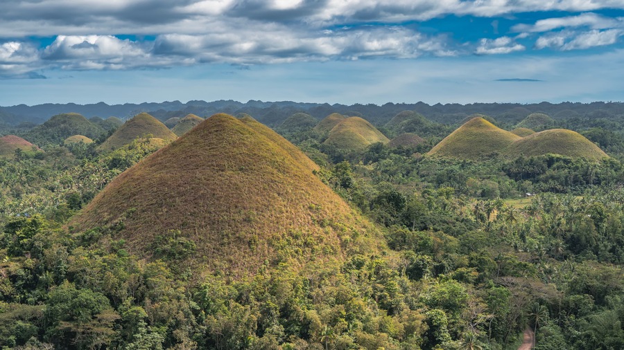 A landscape with multiple conical hills surrounded by dense tropical forest.