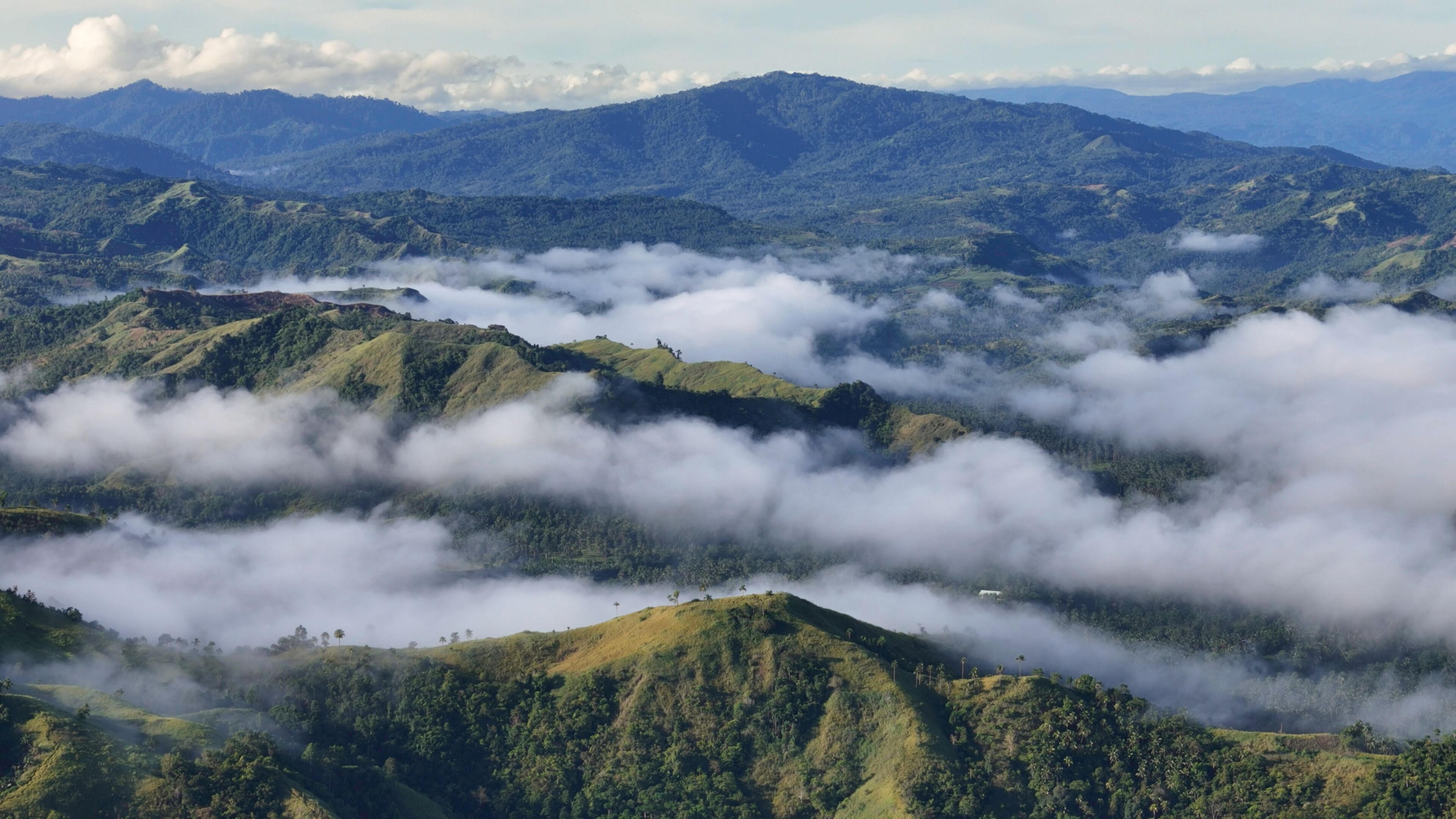 A mountainous landscape with lush greenery and clouds.