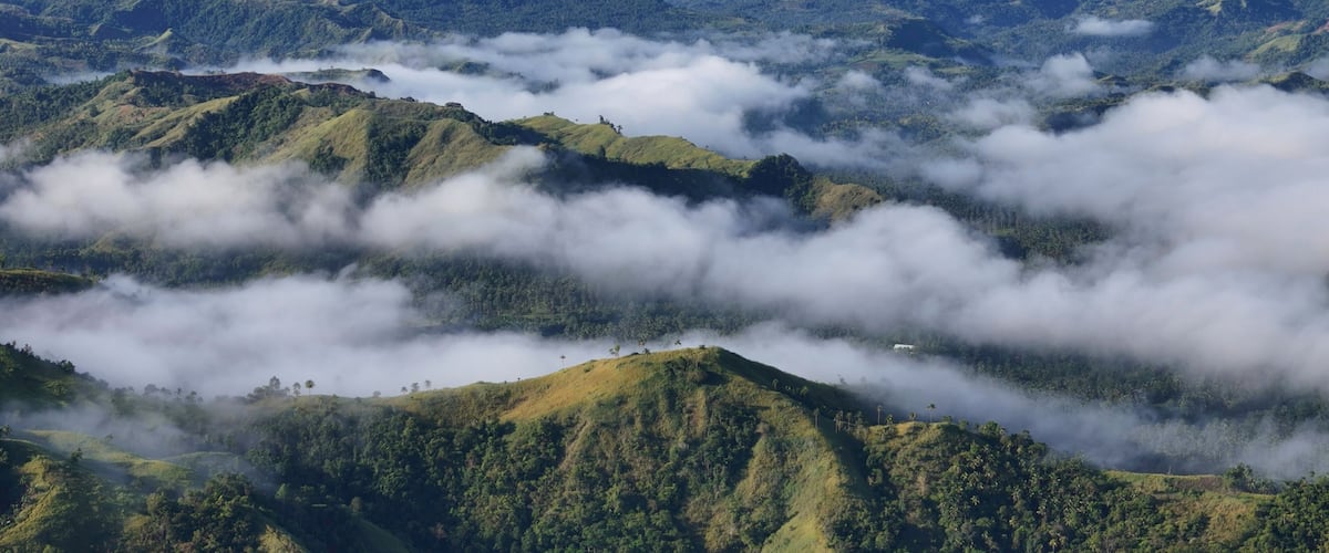 A mountainous landscape with lush greenery and clouds.