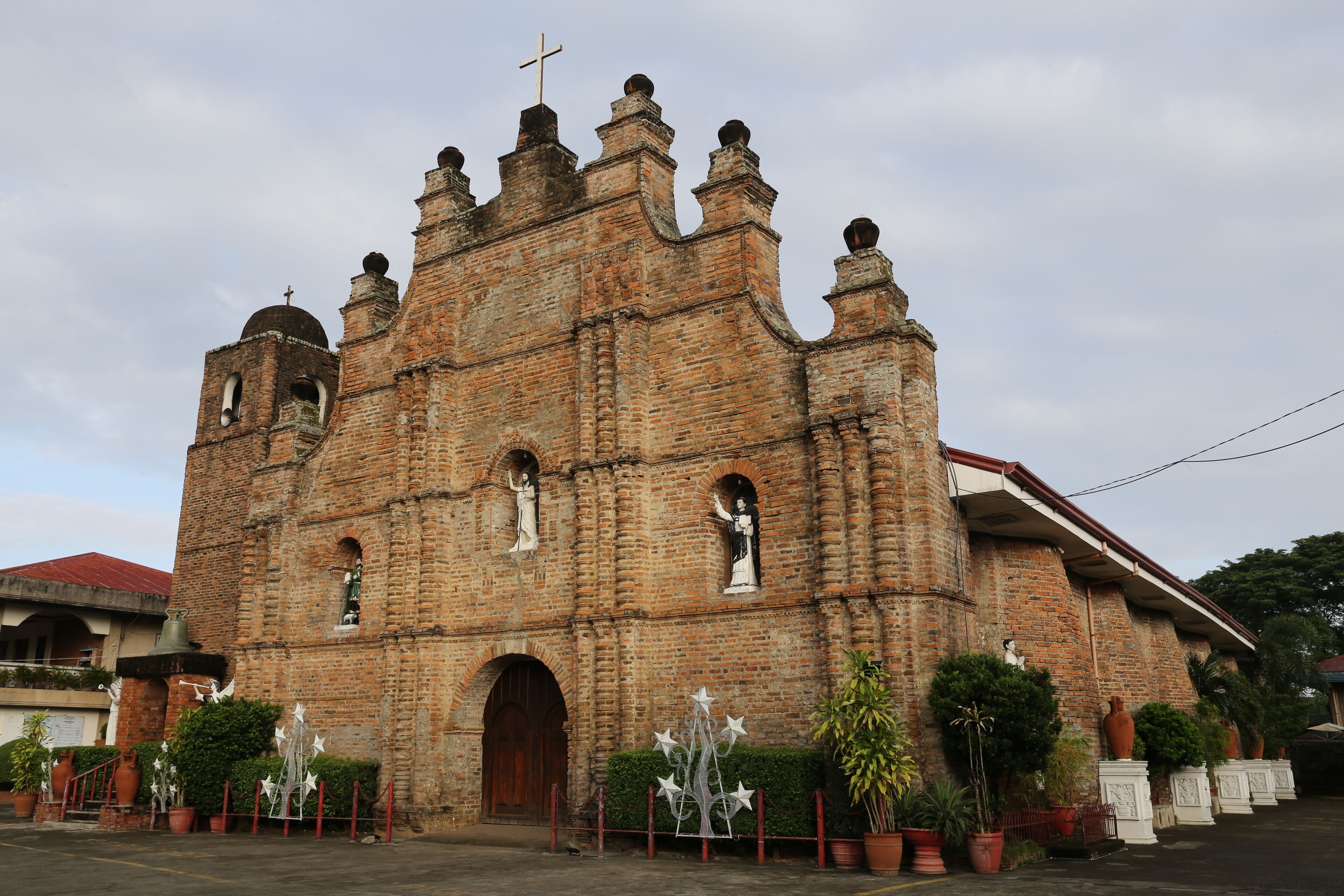 A historic church with a cross on top, brick walls, and statues.
