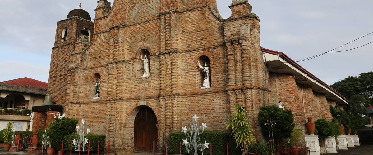A historic church with a cross on top, brick walls, and statues.