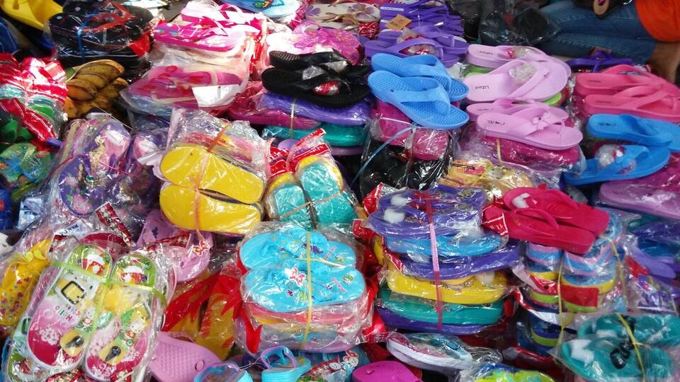 A variety of colorful children's sandals and flip-flops displayed in a market.