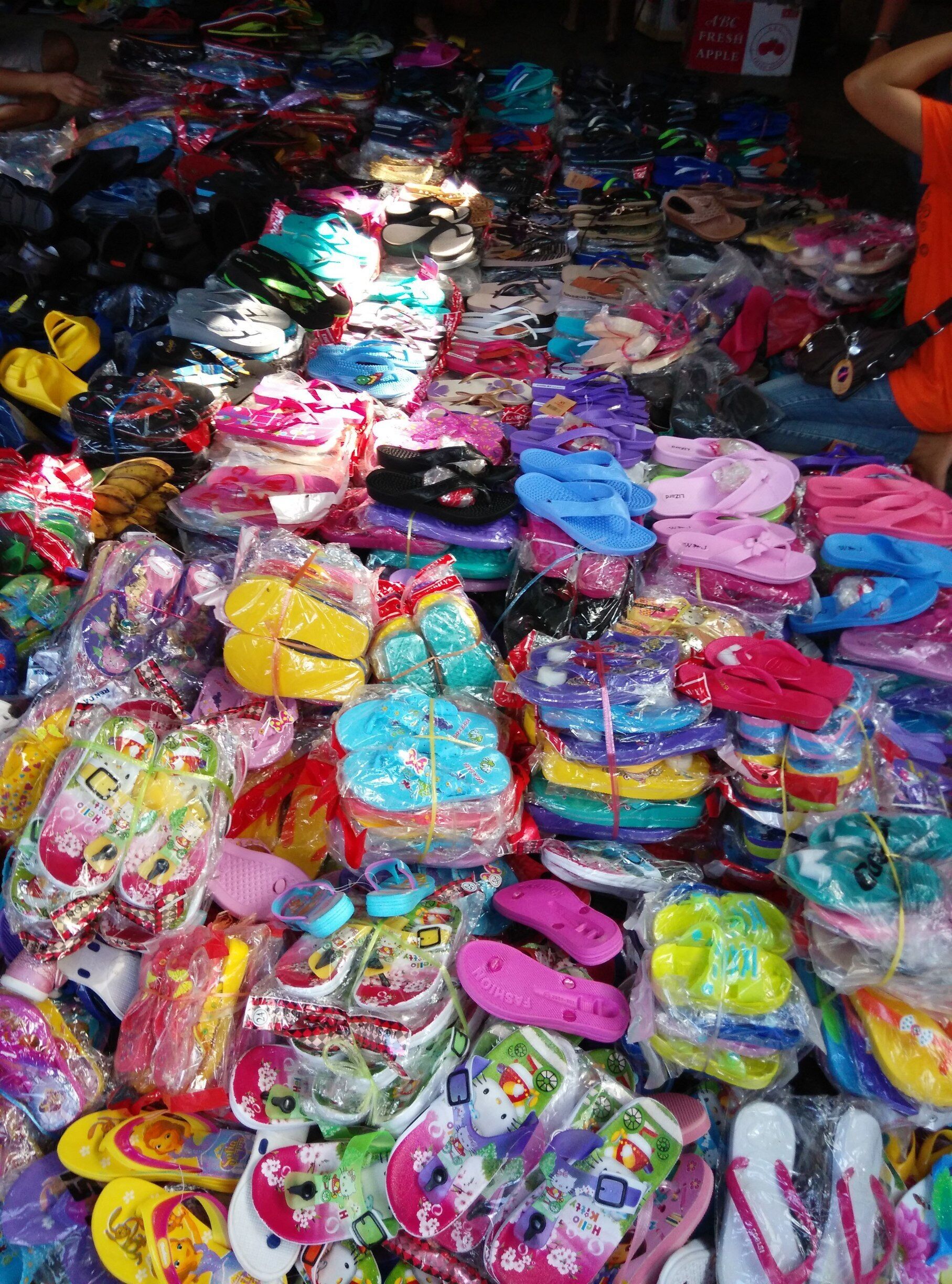 A variety of colorful children's sandals and flip-flops displayed in a market.