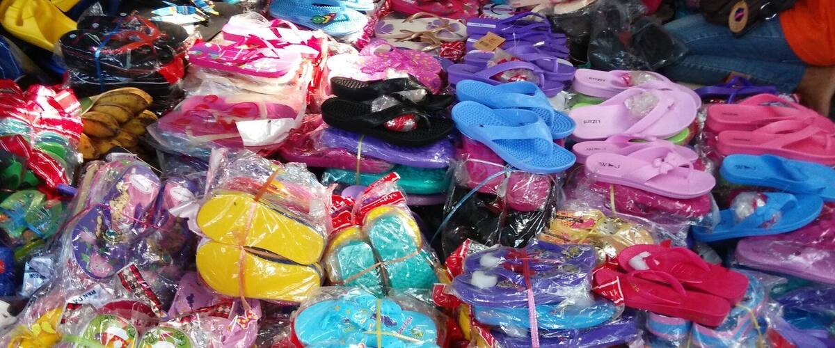A variety of colorful children's sandals and flip-flops displayed in a market.