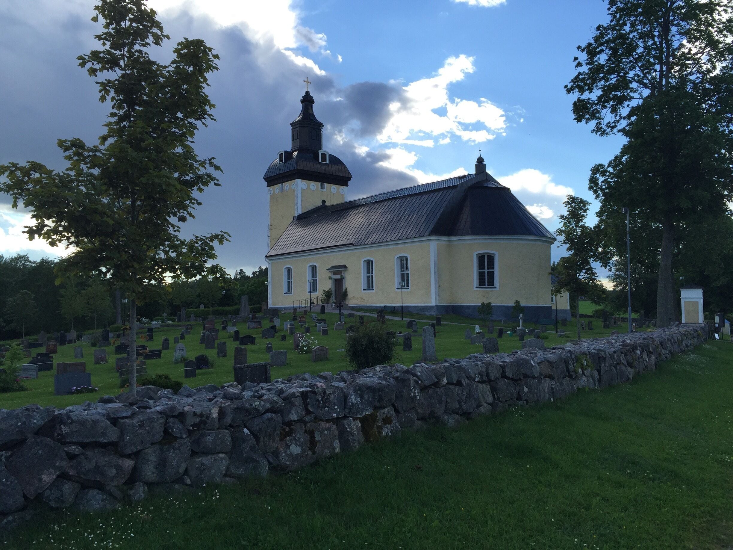 A church with a bell tower and a cemetery in the foreground.