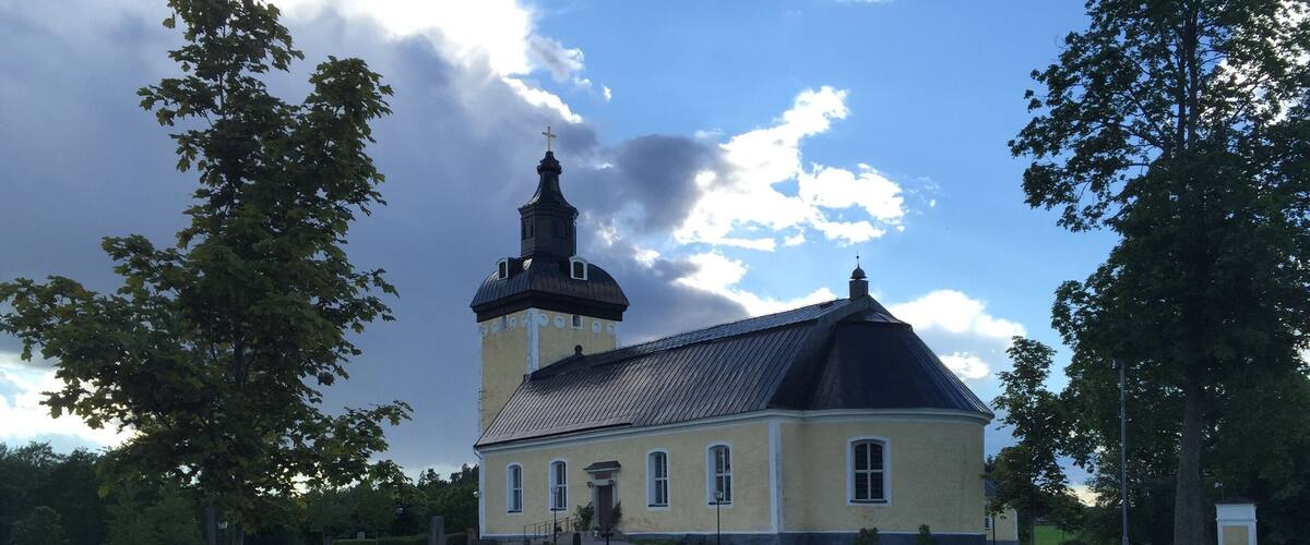 A church with a bell tower and a cemetery in the foreground.