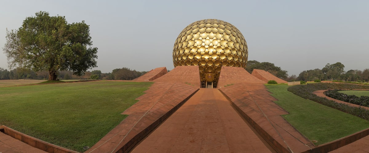 A large golden dome structure surrounded by a landscaped garden with pathways and trees.
