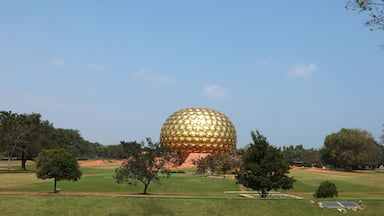 A large golden dome structure surrounded by green grass and trees.