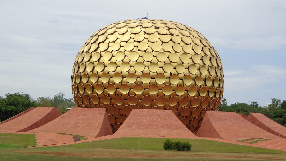 A large golden sphere with a textured surface, surrounded by red pyramidal structures.