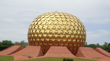 Uma esfera dourada grande com superfície texturizada, rodeada por estruturas piramidais vermelhas.