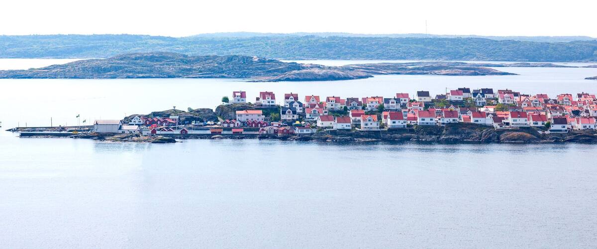 A coastal village with red-roofed houses on a rocky island surrounded by calm water.