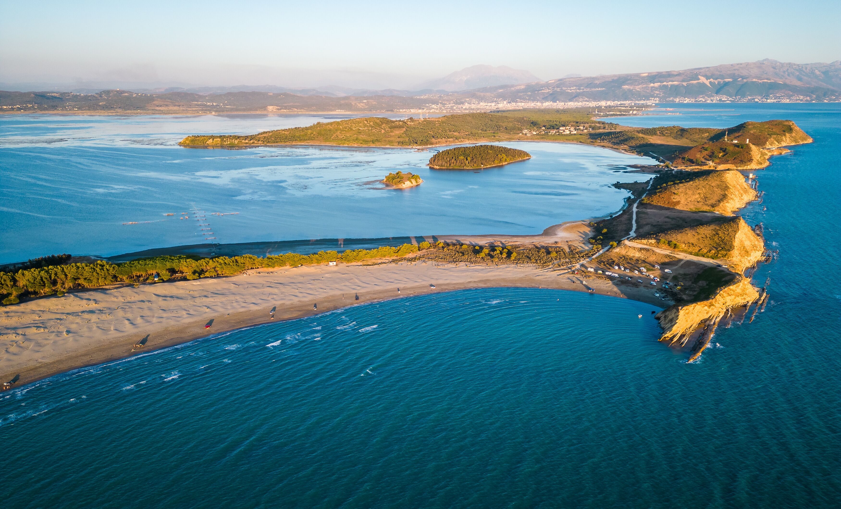An aerial view of a coastal area with a sandy beach, a rocky coastline, and several small islands.