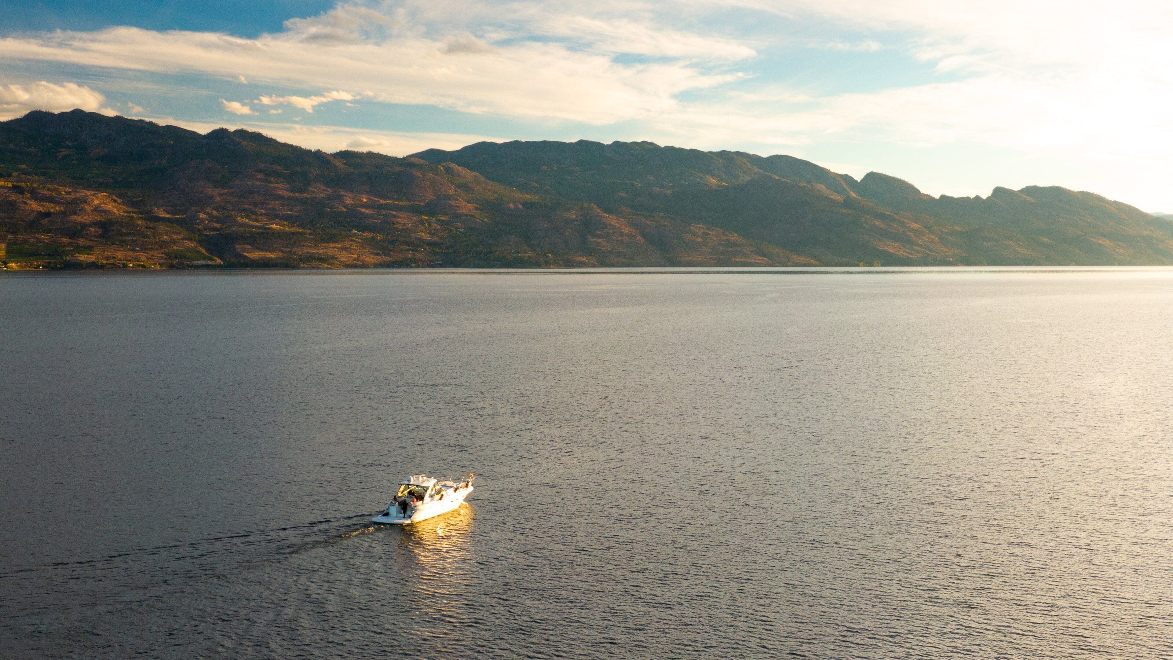 A calm lake with a boat in the foreground and mountains in the background.