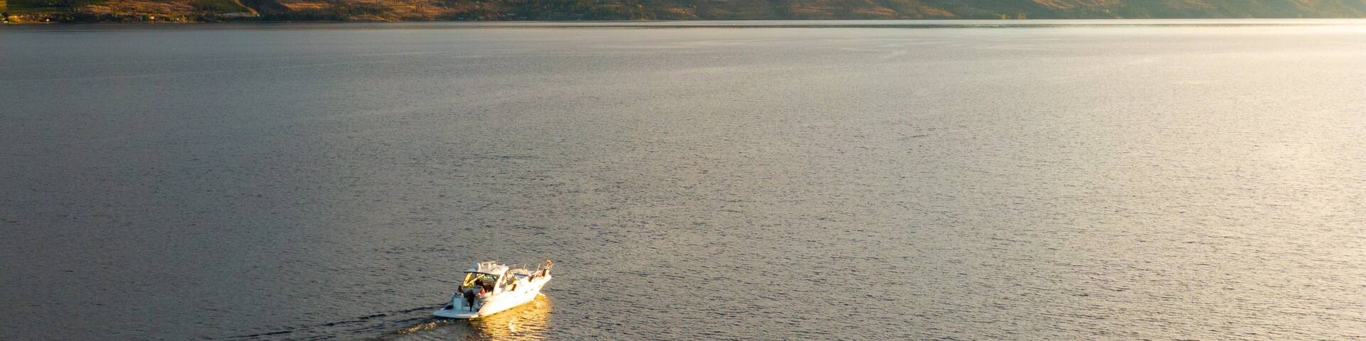 A calm lake with a boat in the foreground and mountains in the background.