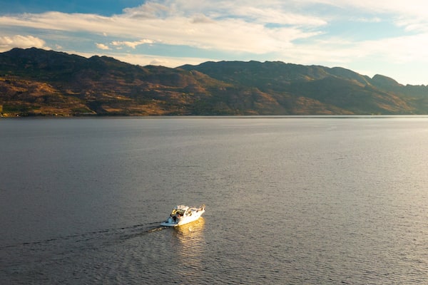A calm lake with a boat in the foreground and mountains in the background.