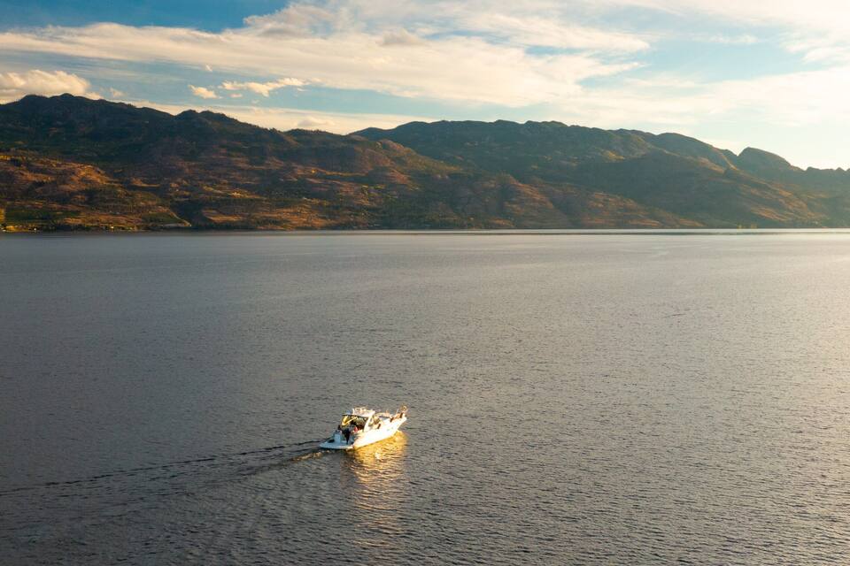 A calm lake with a boat in the foreground and mountains in the background.