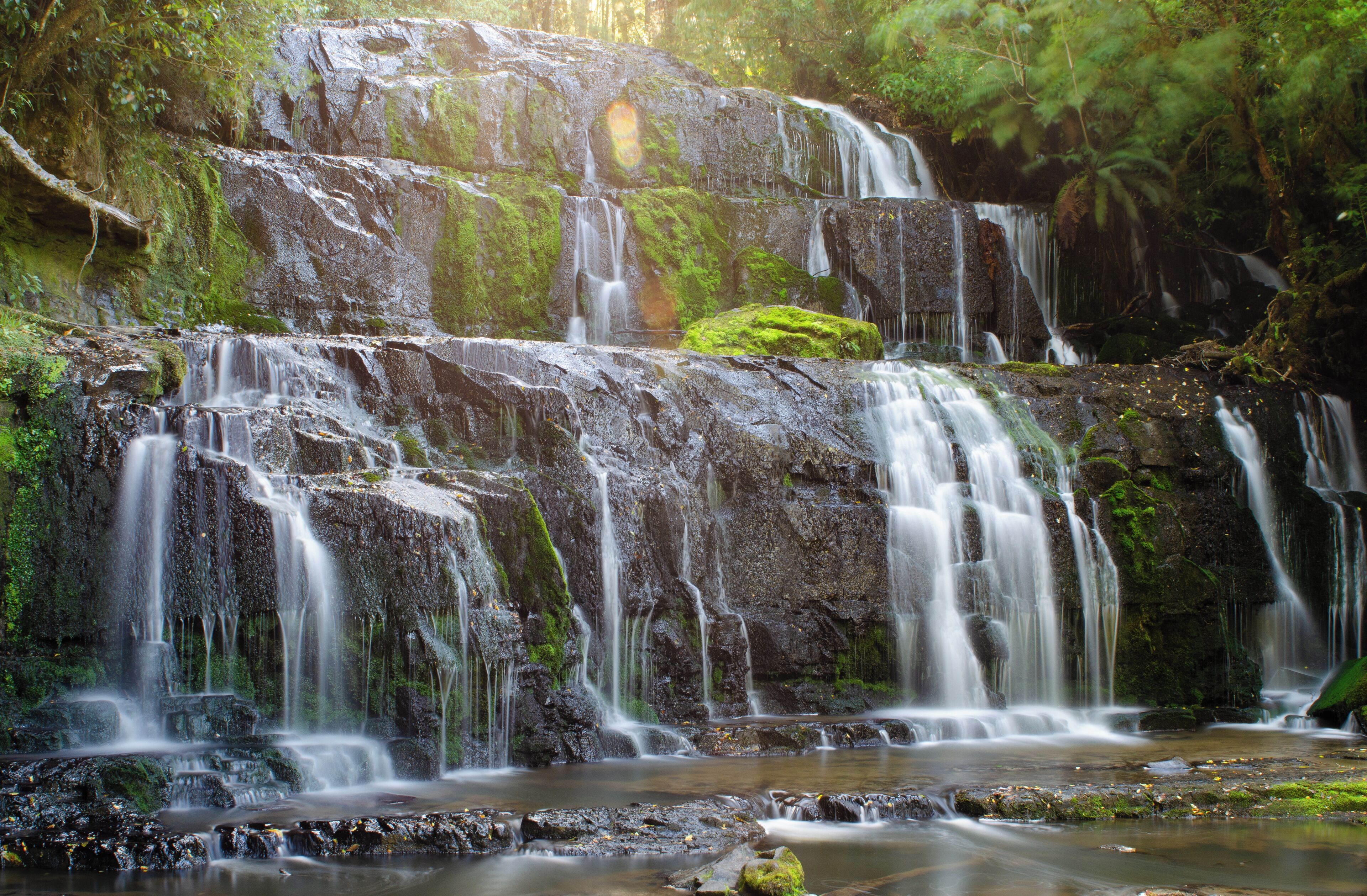 A multi-tiered waterfall surrounded by lush greenery.