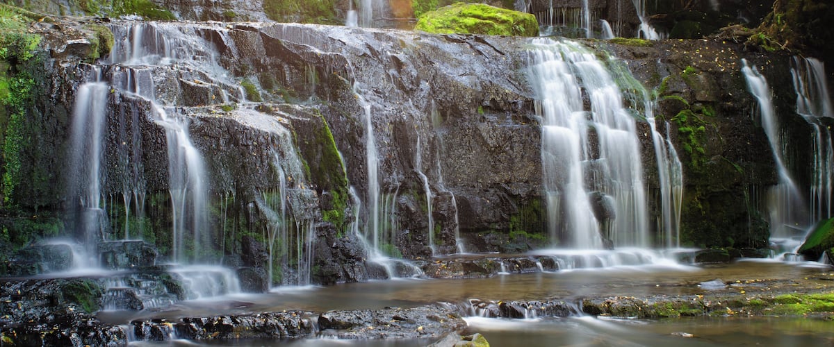 A multi-tiered waterfall surrounded by lush greenery.
