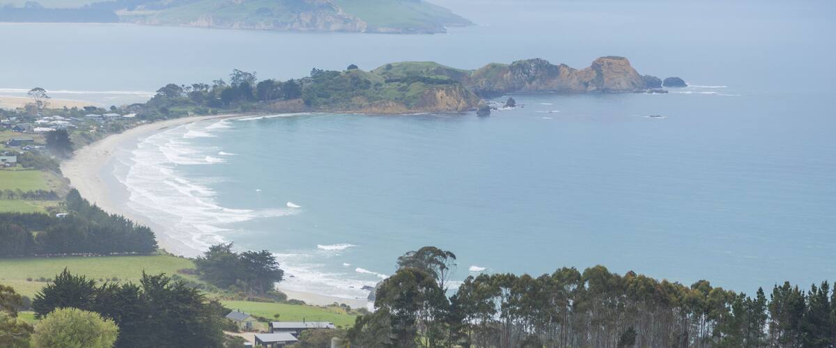 A coastal landscape with a beach, cliffs, and a distant mountain.