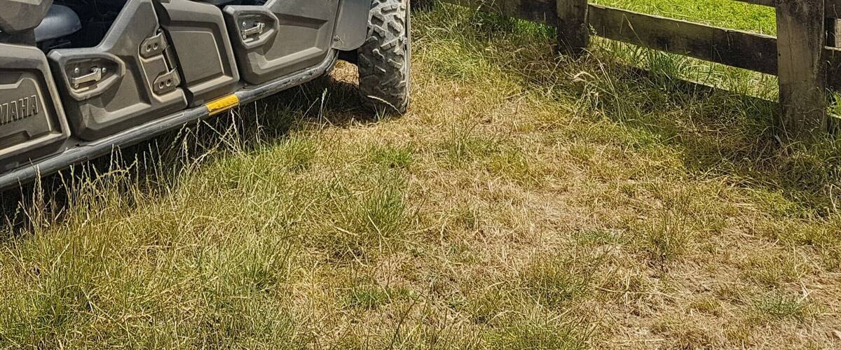 A quad bike parked near a wooden fence with a scenic view of rolling hills and a clear blue sky.