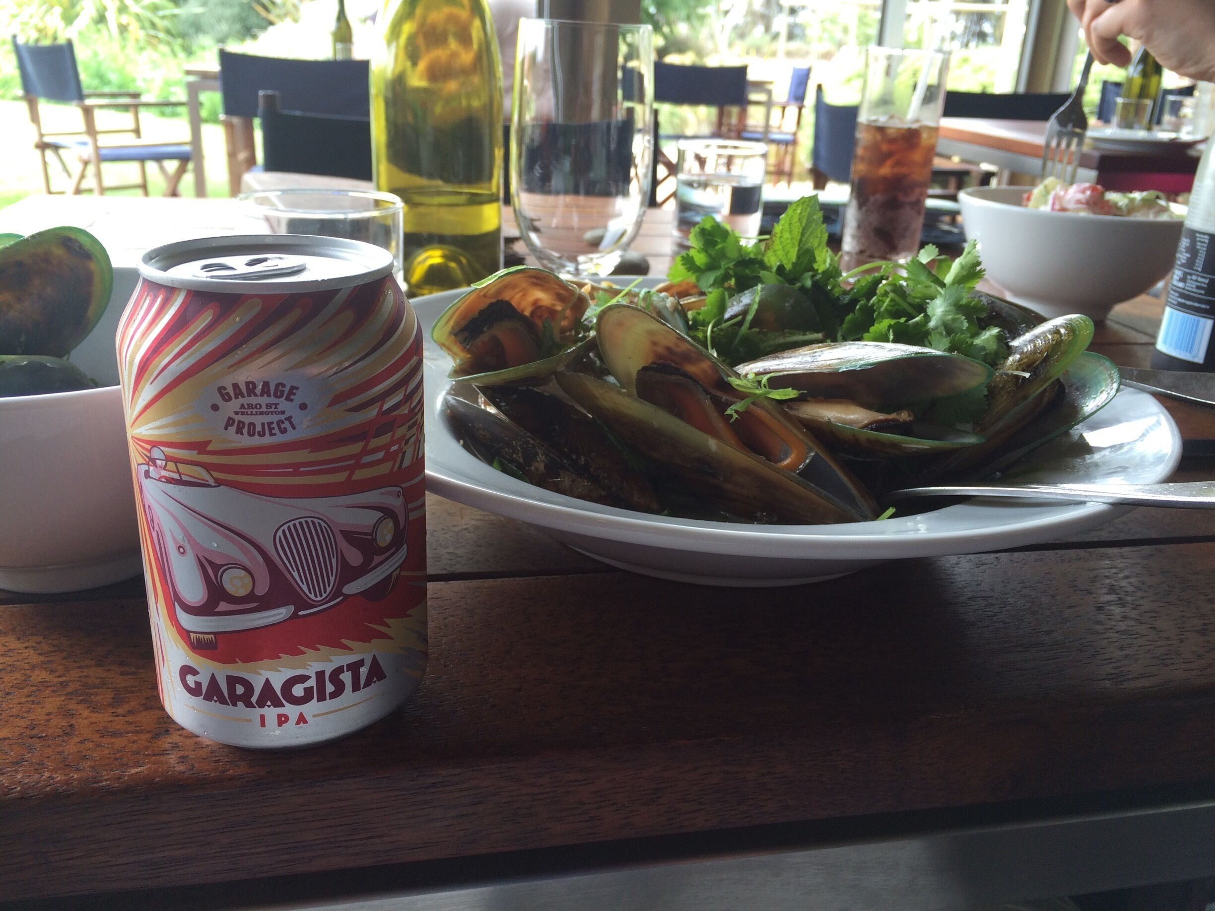 A plate of mussels with a can of Garageista IPA on a table.