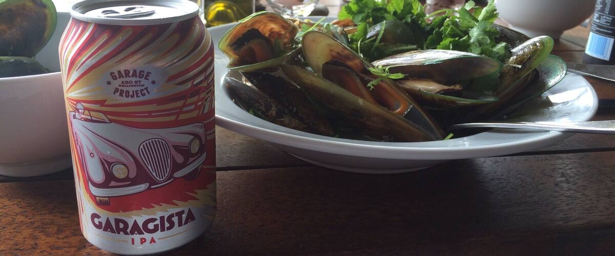 A plate of mussels with a can of Garageista IPA on a table.