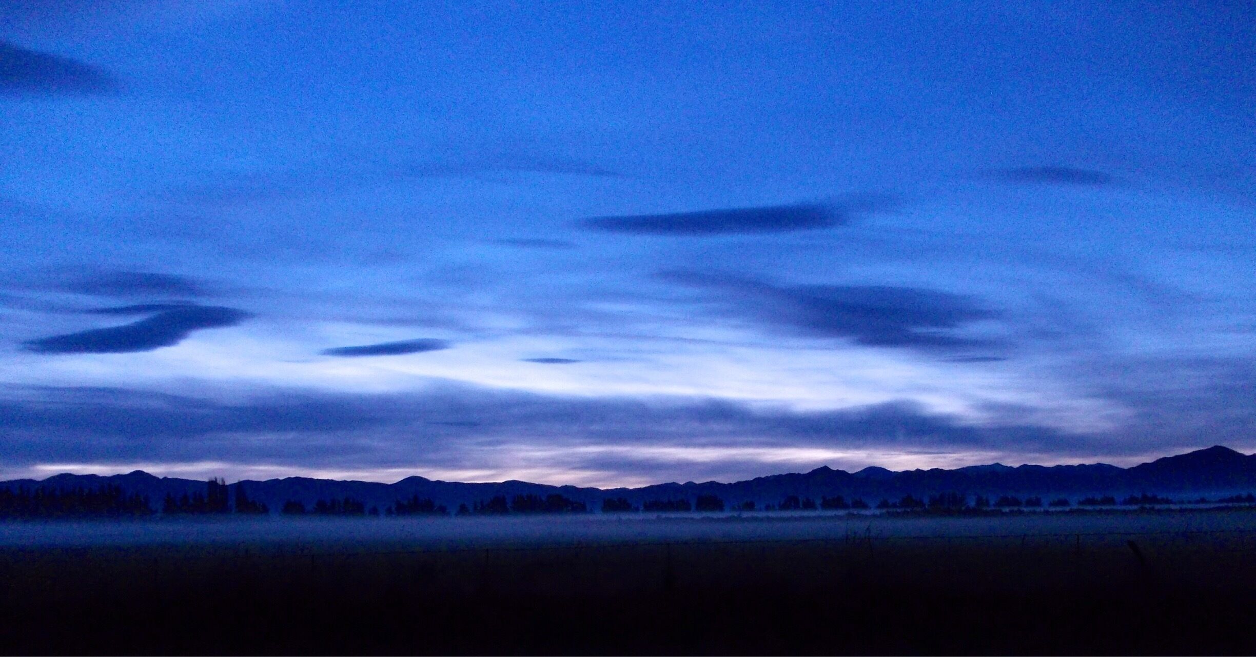 A mountain range at dusk with a clear sky.