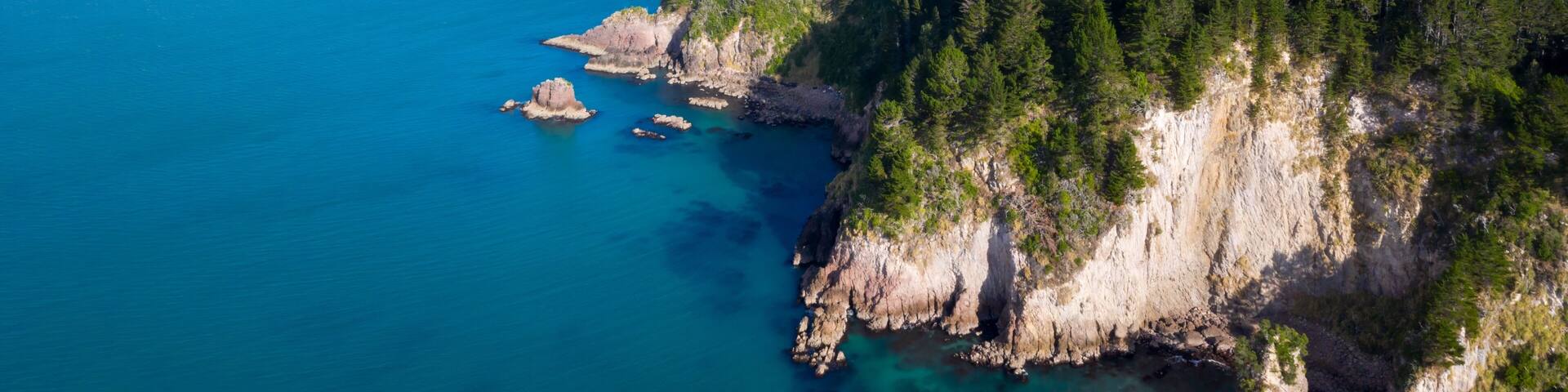 Coastal Coromandel New Zealand scenery. Rocky cliffs meet turquoise water, lush forest. Aerial view. , Whangamata, New Zealand