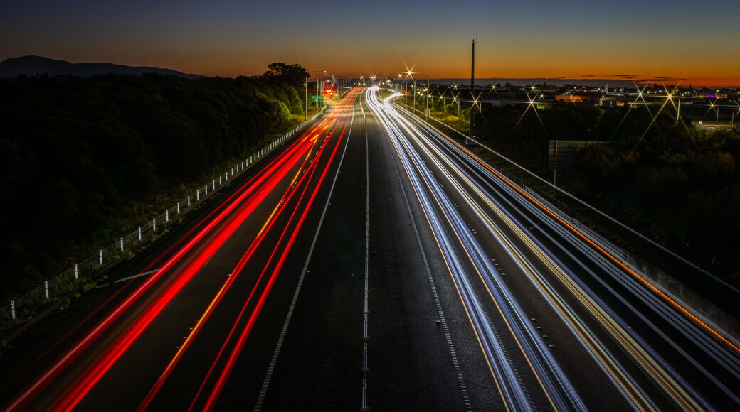 A highway at dusk with light trails from vehicles.