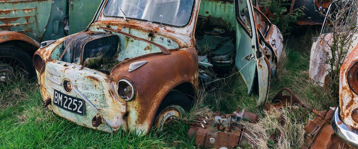 A collection of rusted, abandoned vehicles in a field.