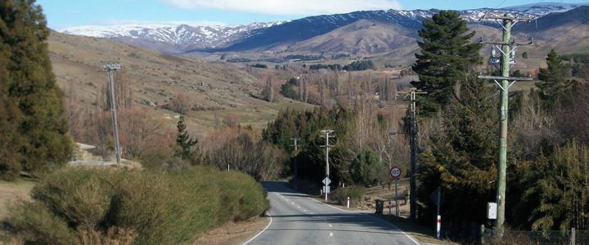 A rural road with a mountain range in the background.