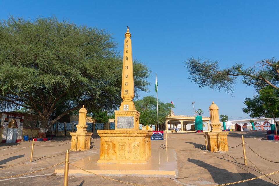 A tall monument with inscriptions, surrounded by trees and a clear blue sky.