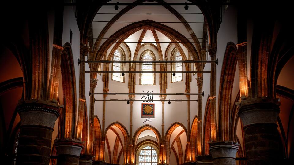 A cathedral interior with arched windows and stone columns.