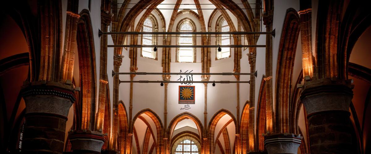 A cathedral interior with arched windows and stone columns.